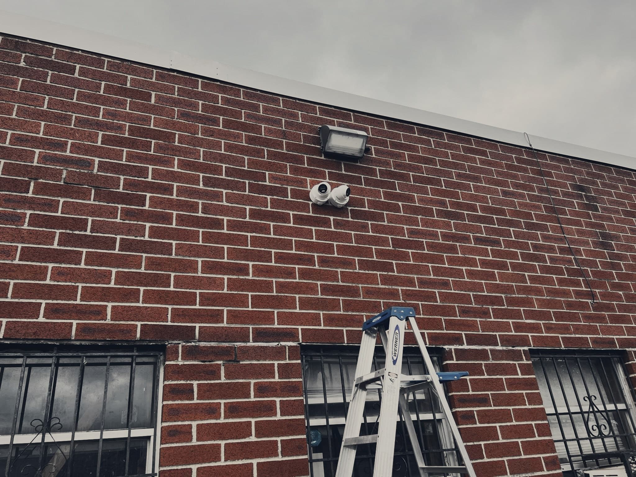 Two security cameras mounted on a brick exterior wall.